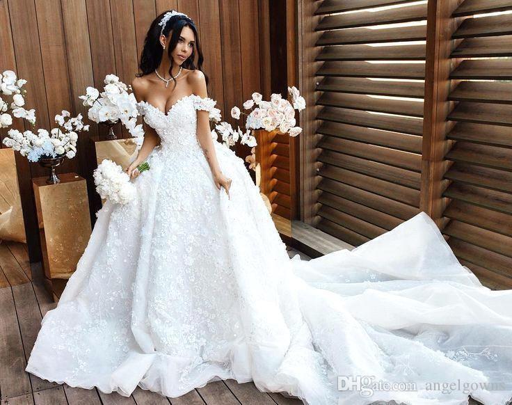 A blushing bride surrounded by white flowers - Sexiest Wedding Dresses 2019